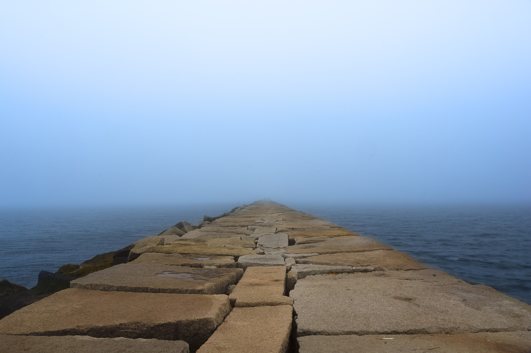 Stone breakwater extending into fog, vanishing at the horizon, Maine