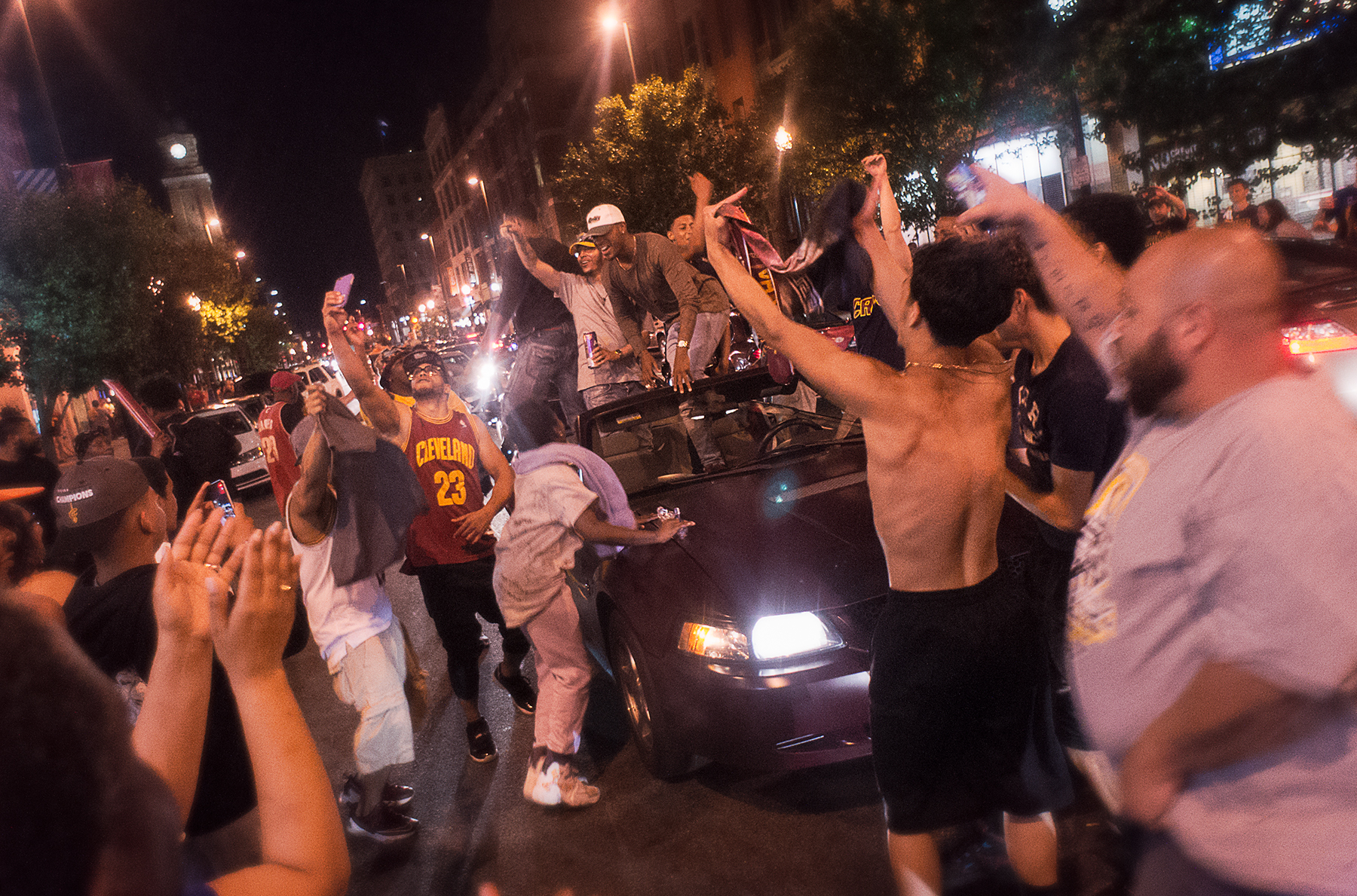 Cleveland fans celebrating in the streets, arms raised, Cavaliers jersey, championship night