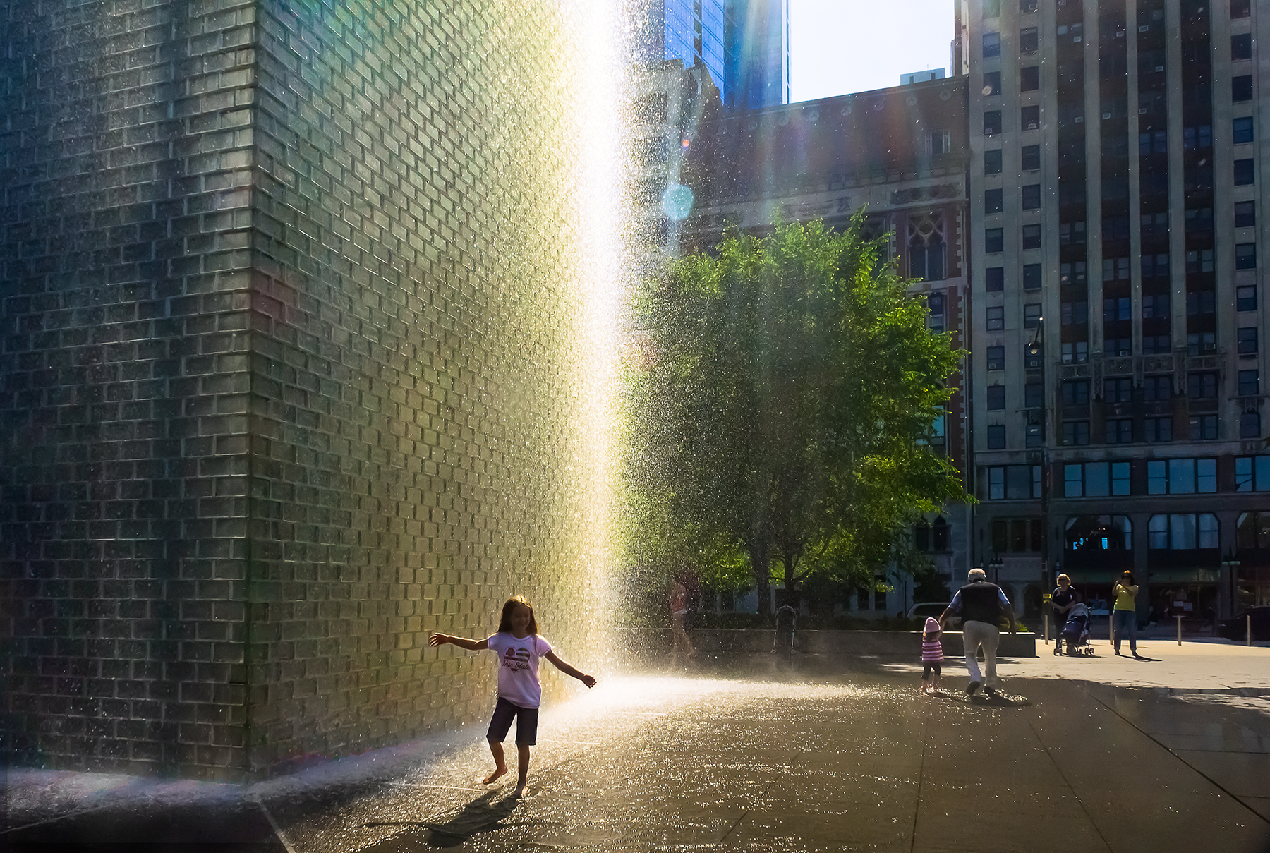 Child silhouetted against water column with rainbow lens flare, Crown Fountain, Millennium Park Chicago