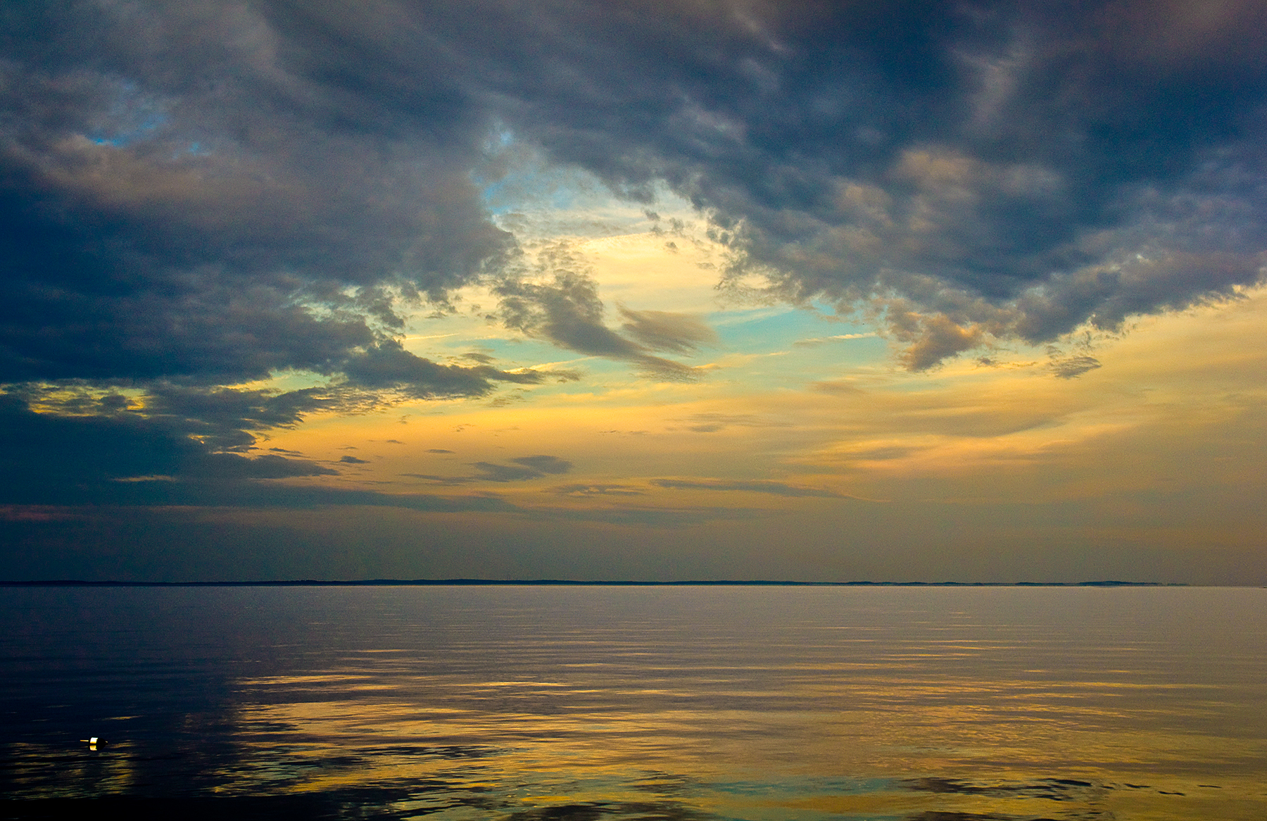 Dramatic storm clouds over still Lake Erie at sunset, golden reflections, Maine breakwall